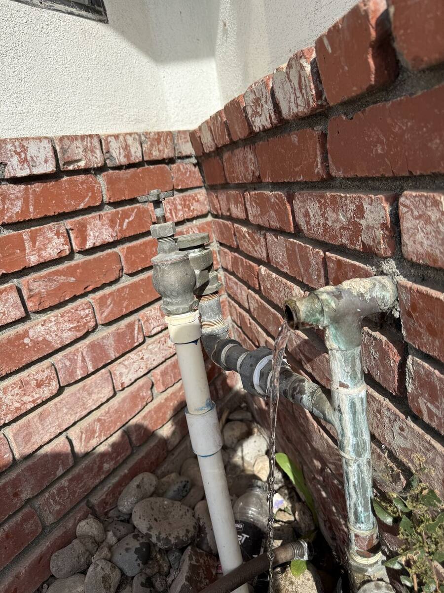 Corroded main water line leaking at a fitting outside a Bakersfield home